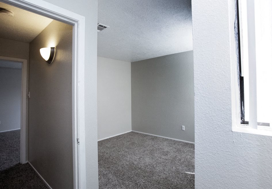 A room with a carpeted floor and a window on the right side.